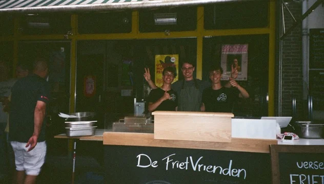 De drie FrietVrienden lachend achter hun zelfgebouwde frietkar