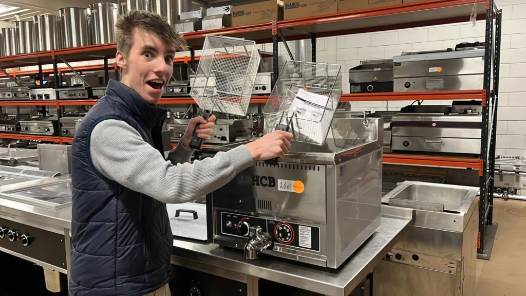 Een van de FrietVrienden bij de bakapparatuur in de werkplaats